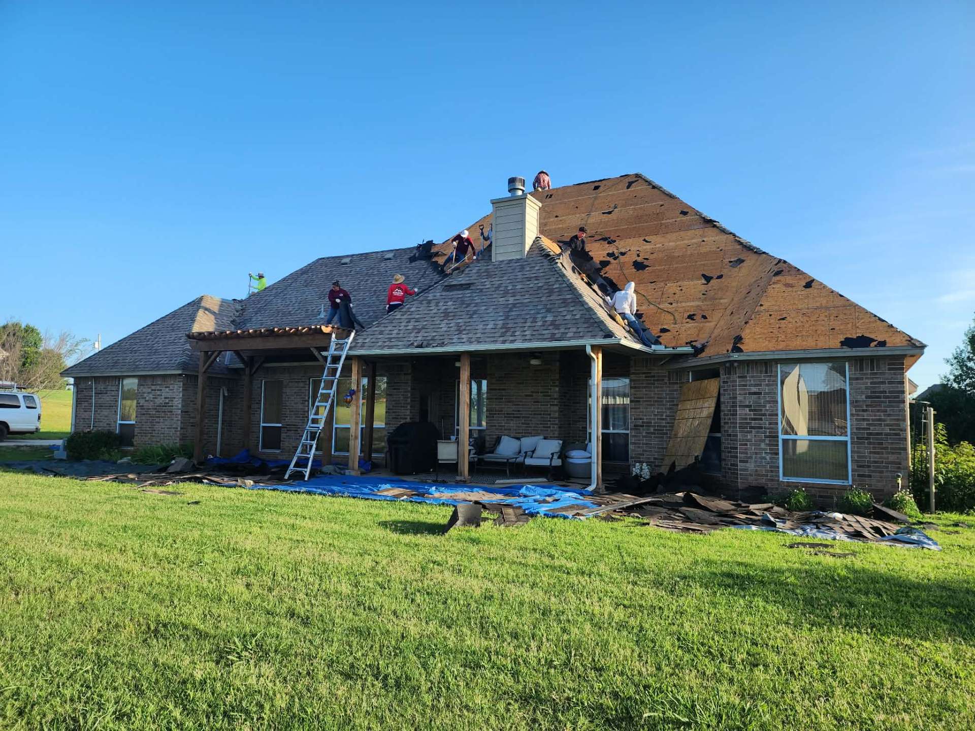 Full tear-off in progress β exposed decking on large hip roof