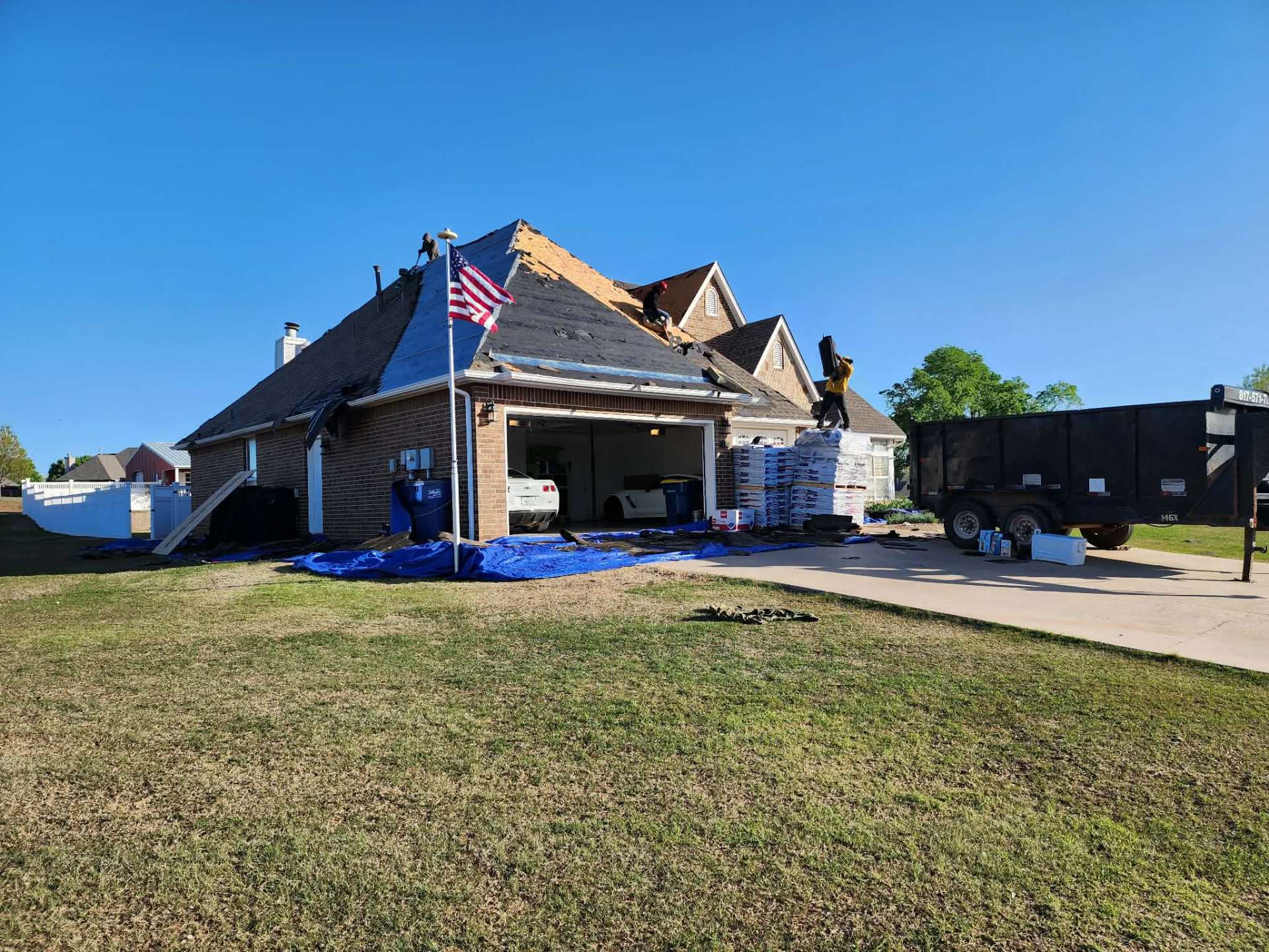 Tear-off day with American flag flying β material staged on driveway